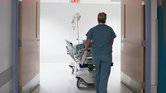 Nurse pushing patient in hospital bed 