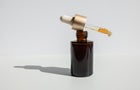 Brown glass with a dropper. Bottle mockup cosmetic oil dropper on a grey background and shadows. Copy space 