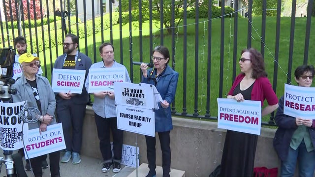 Several faculty members stand at a podium on Columbia University's campus. 
