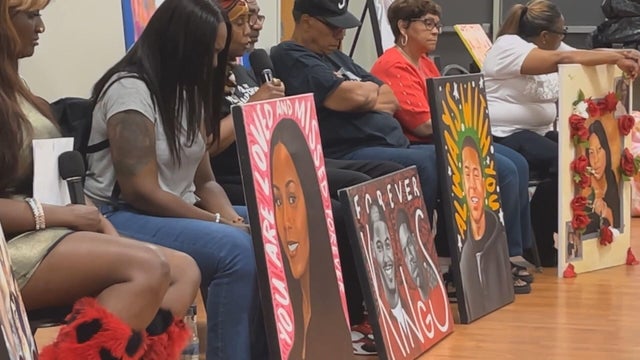 Loved ones sit by portraits of people lost to gun violence, many have their heads bowed 