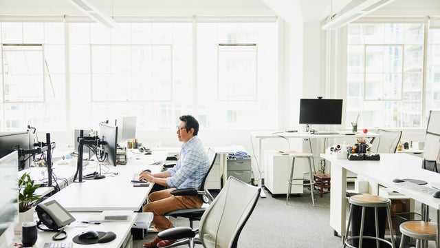 Wide shot businessman working on computer at workstation in office 